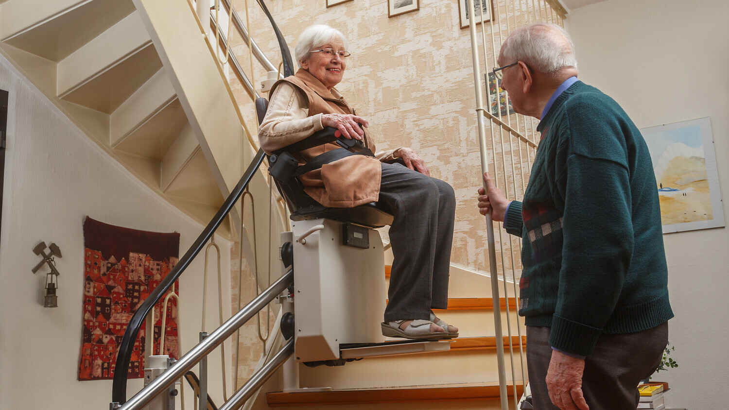 Ältere Dame sitzt angeschnallt auf einem Treppenlift