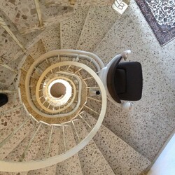 Blick aus der oberen Etage auf eine Wendeltreppe, an der der Sitzlift Klassik installiert wurde