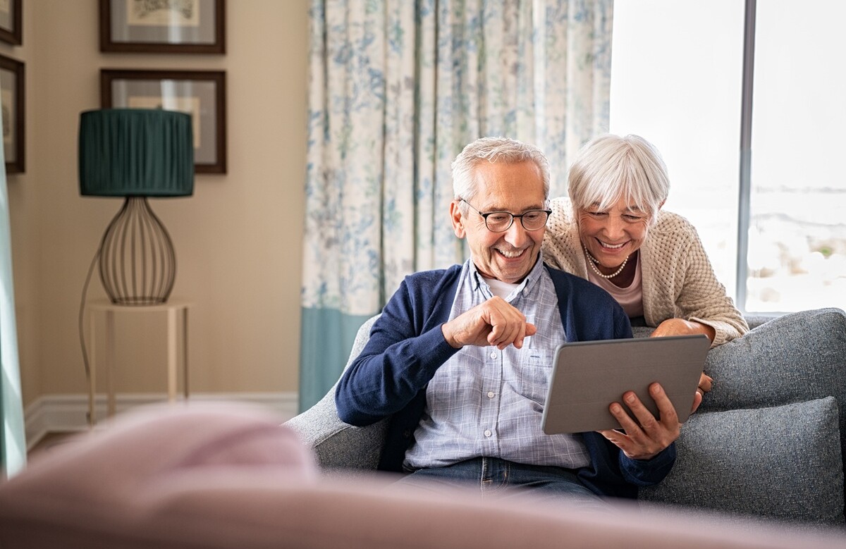 442916239 | © Rido - stock.adobe.com Lächelndes Seniorenpaar schaut zusammen auf ein Tablet